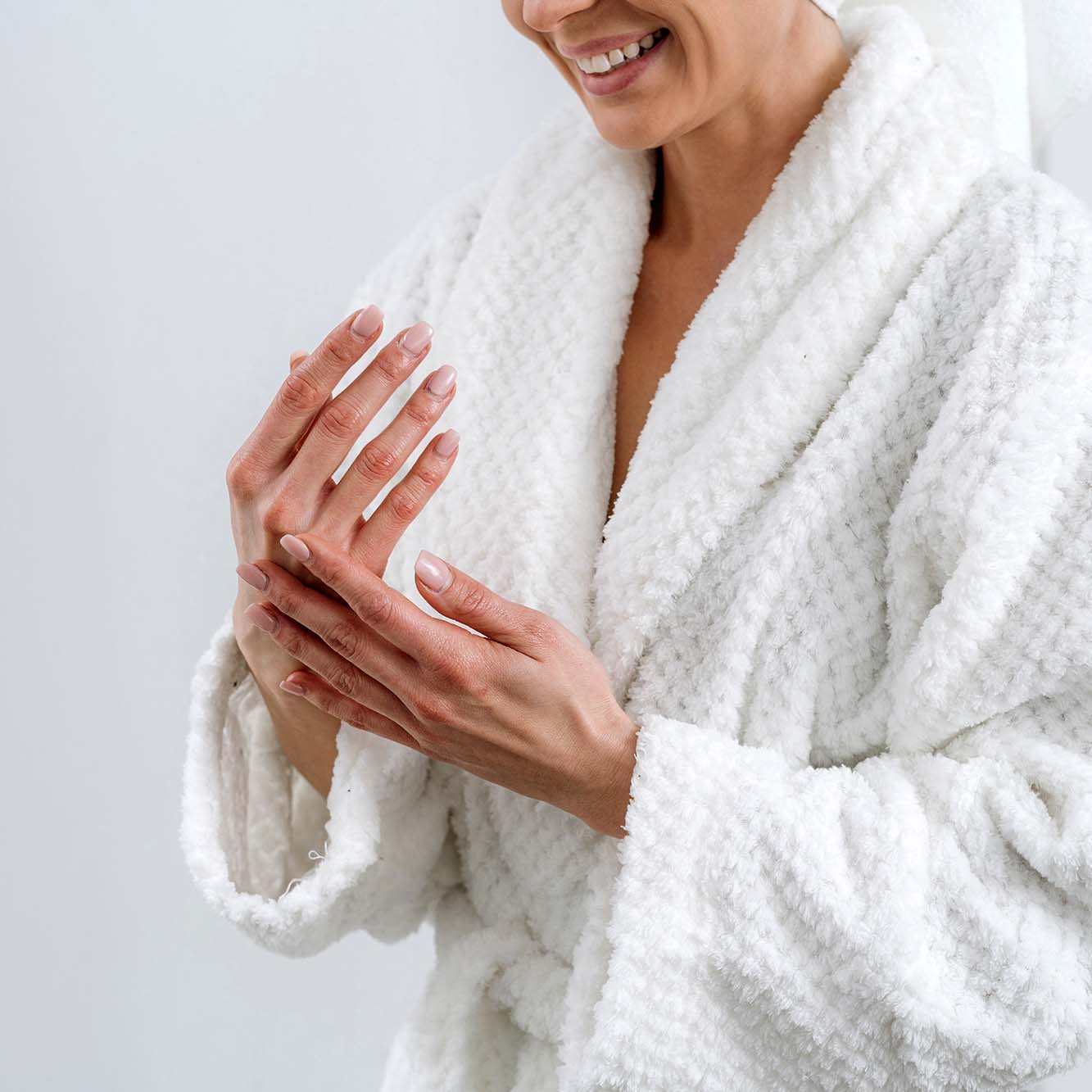 lady putting lotion on hands in a white bath robe